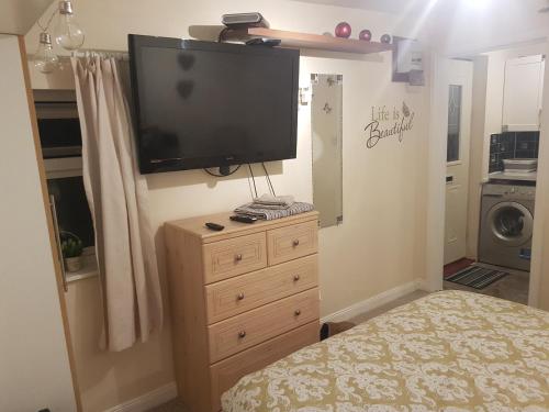 a bedroom with a dresser with a flat screen tv on the wall at Nannys tiny hoose in Inverness