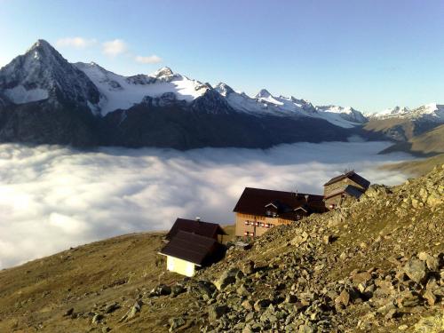 a group of buildings on top of a mountain with clouds at Appartment Venter Bergwelt in Vent