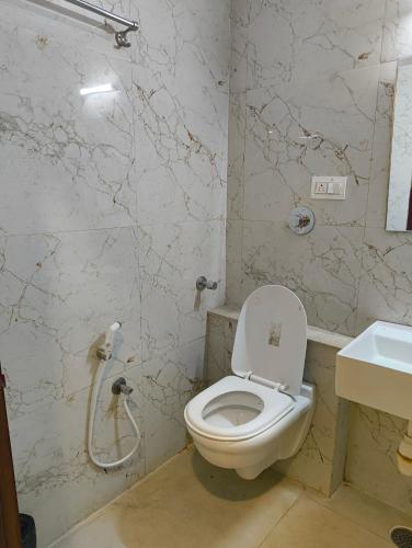 a bathroom with a toilet and a sink at Hotel Cozzy Inn in Bangalore