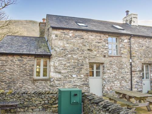 a stone cottage with a picnic table in front of it at Oaktree Cottage-Uk42227 in Low Borrowbridge