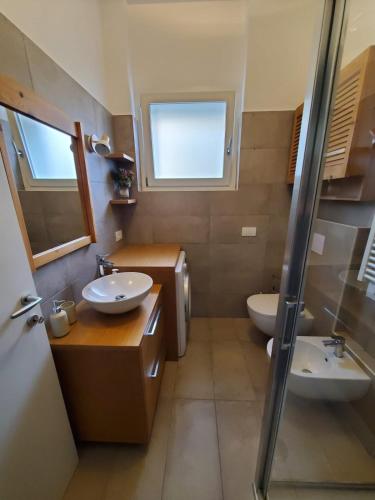 a bathroom with two sinks and a toilet and a window at Appartamento La Camelia in Sondrio
