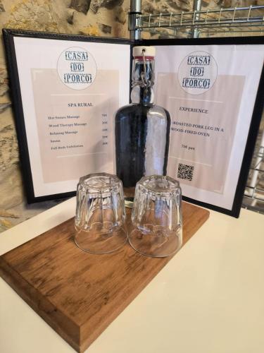 a bottle and two glasses on a wooden cutting board at Casa do Porco - Farm Stay & Spa no Douro in Melres