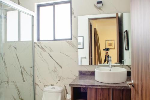 a bathroom with a sink and a toilet and a mirror at Casa feliz 2 in Oaxaca City