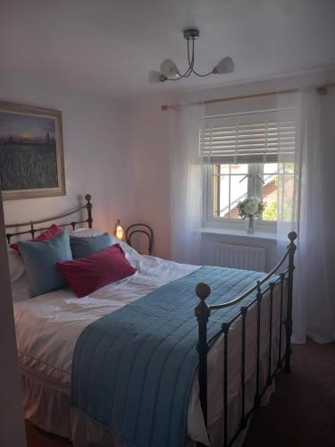 a bedroom with a bed with a blue comforter and a window at Beautiful detached home in Evesham