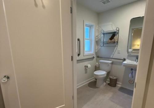 a bathroom with a toilet and a sink and a window at Rochambeau Roadside Inn in Williamsburg