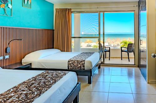 a hotel room with two beds and a balcony with the ocean at Hotel & Suites Domani in Progreso