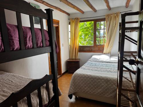 a bedroom with two bunk beds and a window at Hotel Campestre los Duraznos in Cucunubá