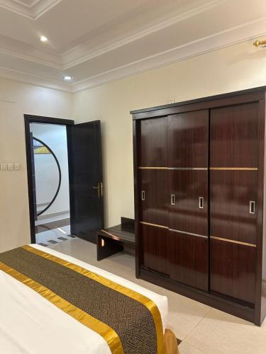 a bedroom with a bed and a large wooden cabinet at كيان الين للشقق المخدومة in Abha
