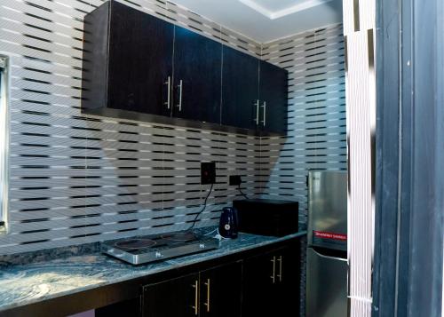 a kitchen with black cabinets and a counter with a refrigerator at Riverside Nest Owerri LTD in Owerri