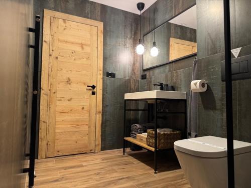 a bathroom with a toilet and a wooden door at Apartmany FABRIK in Vysoká nad Kysucou