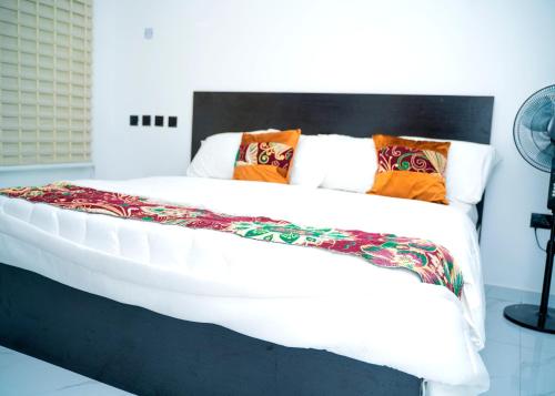a bedroom with a large white bed with colorful pillows at Riverside Nest Owerri LTD in Owerri