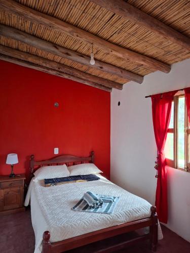 a bedroom with a red wall and a bed at Cabaña Terracota in Maimará