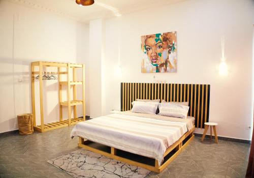 a bedroom with a bed with a painting on the wall at Appartement Moderne Centre ville BZV in Brazzaville