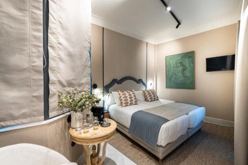 a hotel room with a bed and a table with flowers at De Domínguez Hotel Boutique in Seville