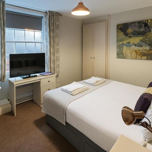 a bedroom with a bed and a desk with a television at The Hand Hotel in Chirk