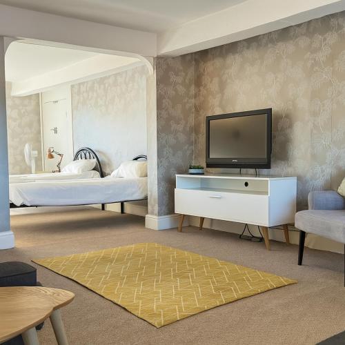 a bedroom with two beds and a television on a wall at The Hand Hotel in Chirk
