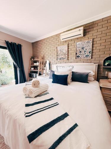 a large white bed in a room with a brick wall at Peach Blossom Guesthouse in Welkom