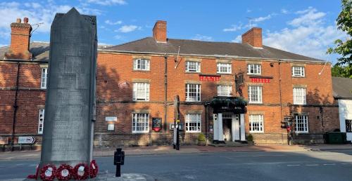 a large red brick building with a monument in front of it at The Hand Hotel in Chirk