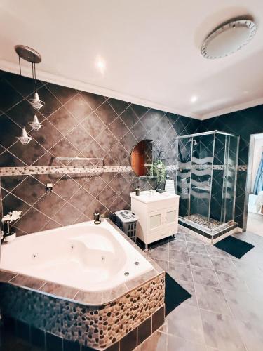 a large bathroom with a tub and a mirror at Peach Blossom Guesthouse in Welkom