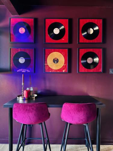 a table with two purple chairs and records on the wall at Le studio rock in Orthez