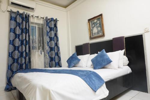 a bedroom with a large bed with blue and white pillows at Complexe A8CLOS in Douala