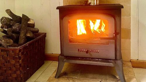 a woodburning stove next to a basket of logs at Sea Roots "Garden Zone " in Mosteiros