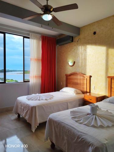 a hotel room with two beds and a large window at Hotel Pampa & Selva in Rurrenabaque