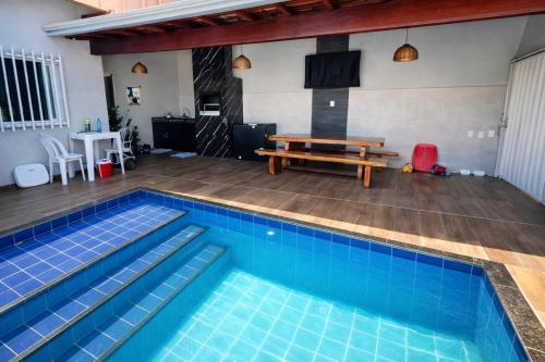 a swimming pool with a picnic table and a bench at Casa inteira com Piscina - 3 Quartos - Área Gourmet - 5 min da Praia in Prado