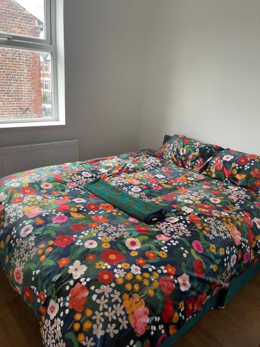 a bed with a flowered comforter on top of it at Princess shahzadi in Manchester