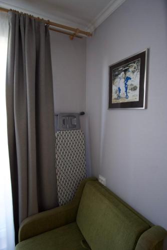 a room with a green chair and a curtain at Apartments in Kauguri in Jūrmala