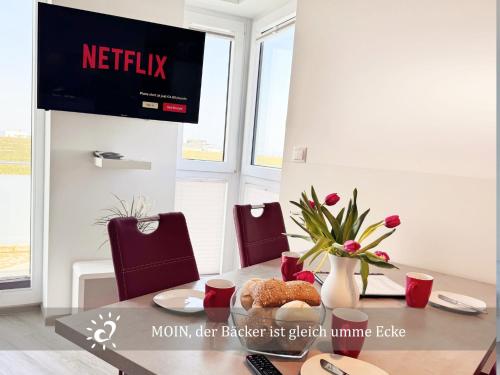 a dining room table with a television on a wall at Penthouse de Ool Blick auf das Wattenmeer in Neufeld