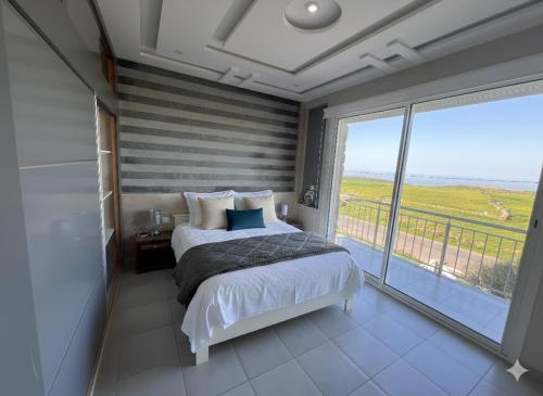 a bedroom with a bed and a large window at DreamCatcher Paragliders in Tamelalt