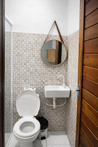 a bathroom with a toilet and a sink and a mirror at Pousada Areias de Amaro in Santo Amaro