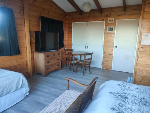 a room with two beds and a television and a table at Riverside Loft in Turangi