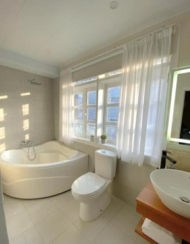 a bathroom with a tub and a toilet and a sink at Khu Hòa Bình in Da Lat