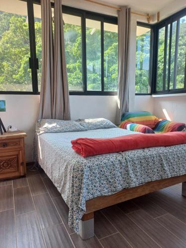 a bed in a room with windows and a bed sidx sidx sidx sidx at Estudio La Higuera in Yelapa