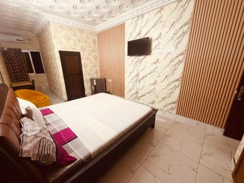 una camera da letto con un letto e una TV a parete di Bethany Hotel a Abidjan