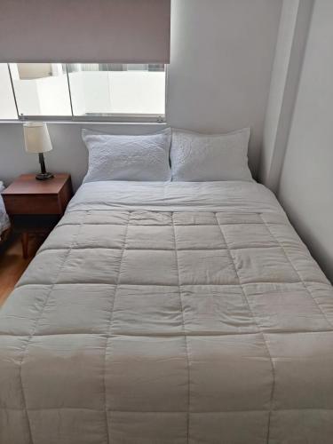 a bedroom with a large bed with a white comforter at Miraflores View in Lima