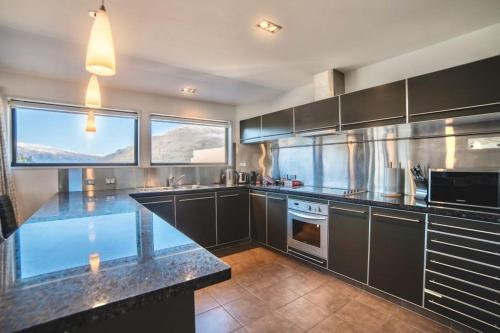 a kitchen with black cabinets and a counter top at Lakefront Luxury Penthouse central Queenstown in Queenstown