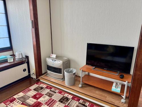 a living room with a flat screen tv and a table at ANFT-shiro in Azumino