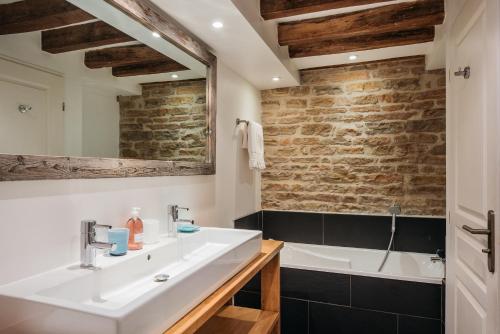 a bathroom with a white sink and a bath tub at Hôtel Le Clos du Colombier 1817 Vignes & Spa in Pommard