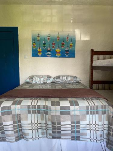 a bed with two pillows and a painting on the wall at Suítes Sabor e Mar in Angra dos Reis