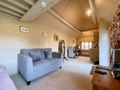 a living room with a blue couch and a table at Oaklands Farm - Cottage 4 in Broughton