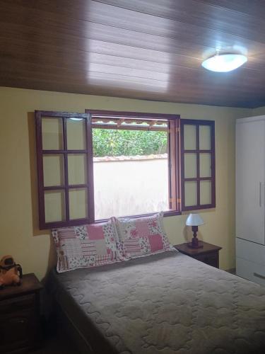 a bedroom with a bed with pillows and a window at Hospedagem do Rio in Nova Friburgo