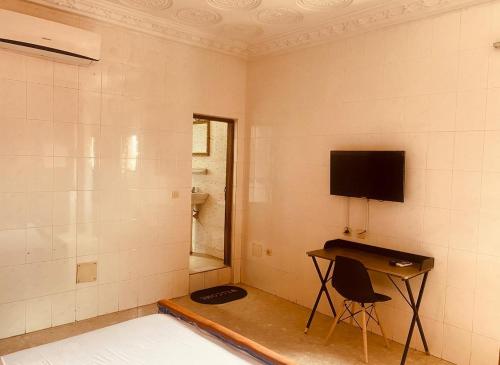 una stanza con una televisione e una scrivania con una sedia di Bethany Hotel a Abidjan