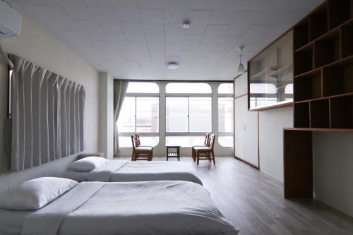 a bedroom with two beds and a table and chairs at 南栄駅1分 3寝室 最大9名 キッチン付一棟貸し パーキング1分 Showa Retro Japanese House 1min Station Entire Home for 9 in Toyohashi