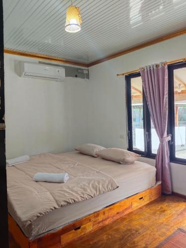 a bed in a room next to a window at Djambu Tree Homestay in Biha
