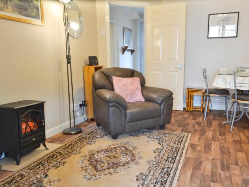 a leather chair sitting in a living room with a fireplace at Ashley Cottage in Bowmore