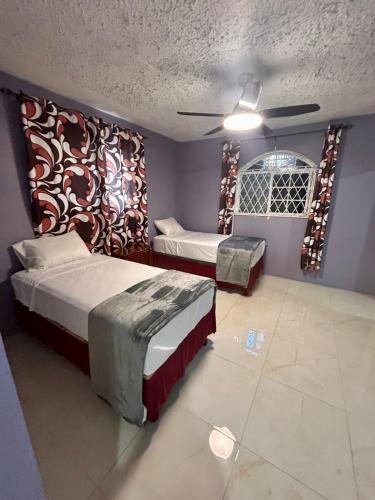 a bedroom with two beds and a ceiling at Coke Guest House in Mandeville