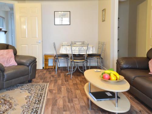 a living room with a couch and a table with a bowl of fruit at Ashley Cottage in Bowmore